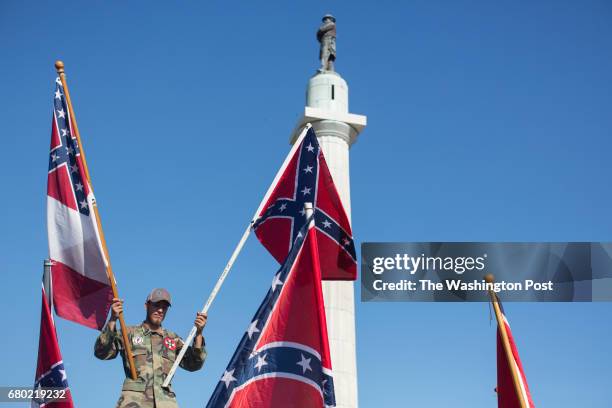 Person in opposition to the removal of monuments to the Confederacy holds confederate flags against the Robert E. Lee statue in New Orleans,...