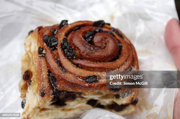 chelsea bun held in a man's hand - sweet bun stock-fotos und bilder