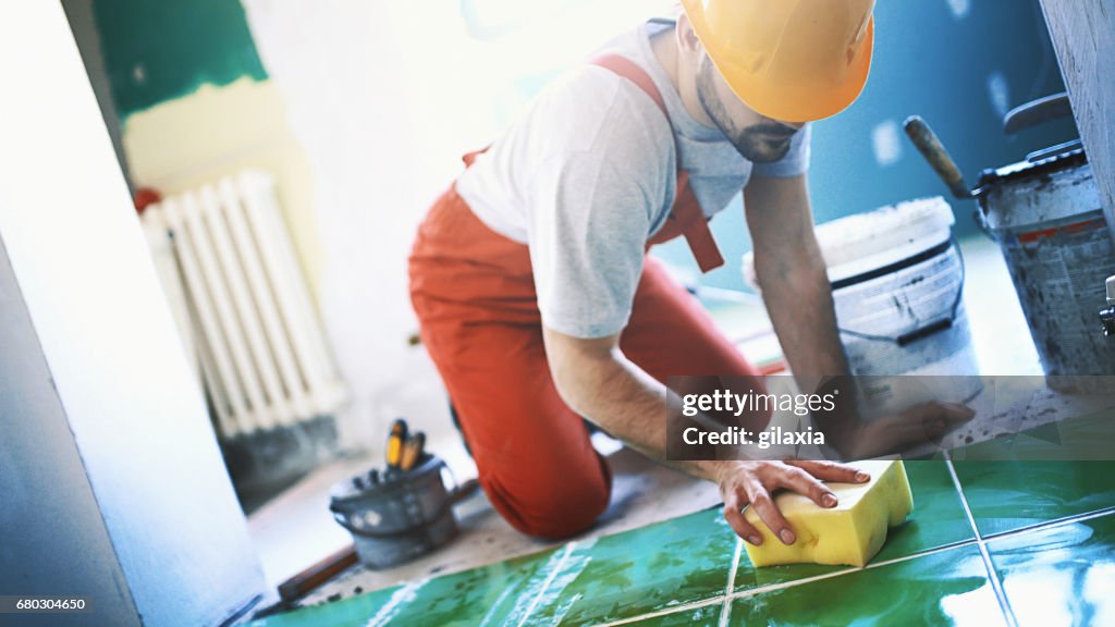 Handyman installing ceramic tiles.