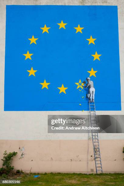 Graffiti artist Banksy has unveiled his latest piece about Brexit in Dover, United Kingdom. The artwork shows a man up a ladder chipping a gold star...