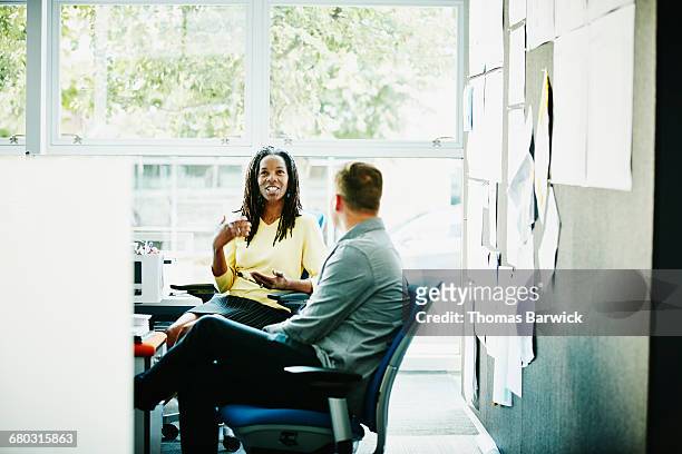 coworkers discussing project at workstation - leanintogether stock pictures, royalty-free photos & images