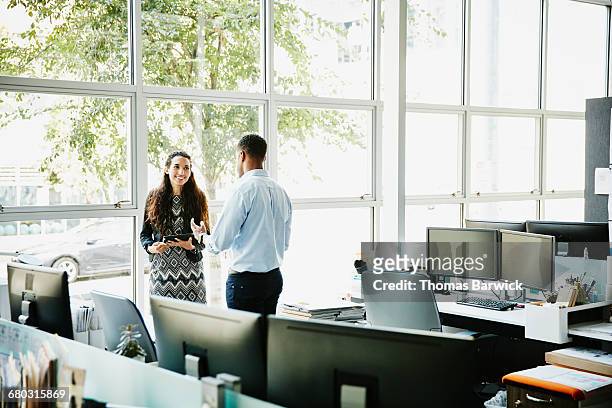 coworkers discussing project at office workstation - leanintogether stock pictures, royalty-free photos & images