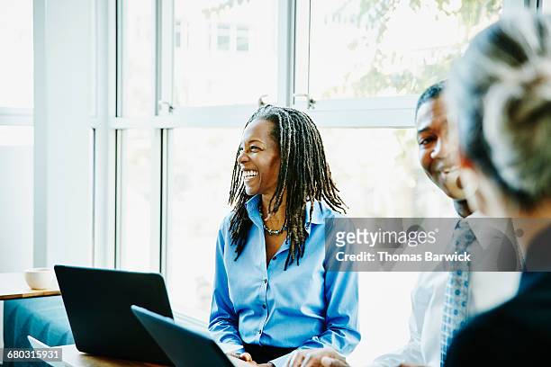 laughing businesswoman in team meeting in office - coinvolgimento dei dipendenti foto e immagini stock