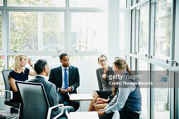 mature businesswoman leading team meeting - colleagues supporting stockfoto's en -beelden