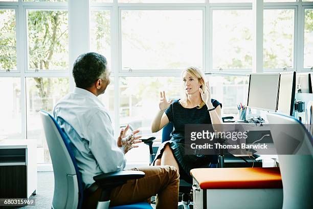 businesswoman in discussion with coworker - leanincollection stock pictures, royalty-free photos & images