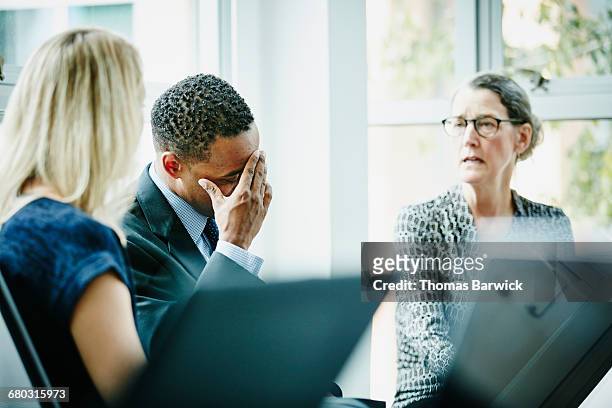 businessman with head in hand during meeting - public scrutiny stock pictures, royalty-free photos & images