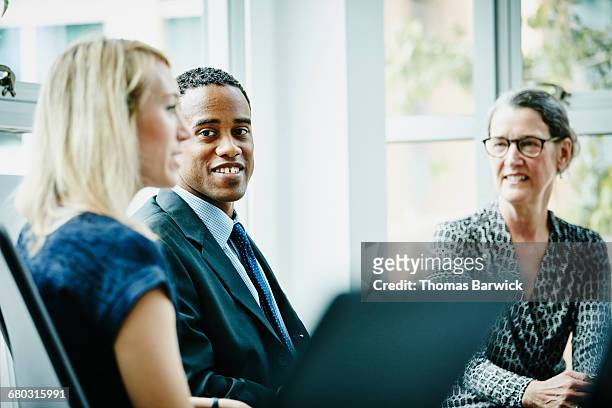 smiling businessman listening to colleague - leanintogether stock pictures, royalty-free photos & images