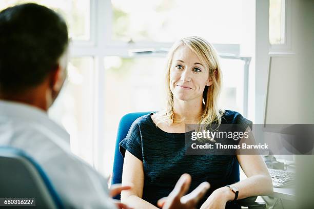 smiling businesswoman listening to colleague - insight guidance stock pictures, royalty-free photos & images