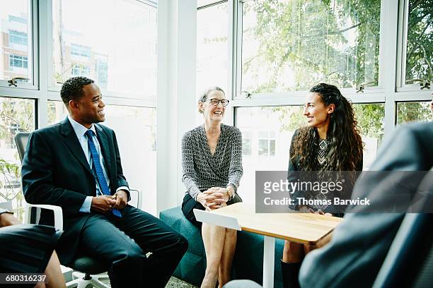smiling mature businesswoman leading team meeting - leanintogether stock pictures, royalty-free photos & images