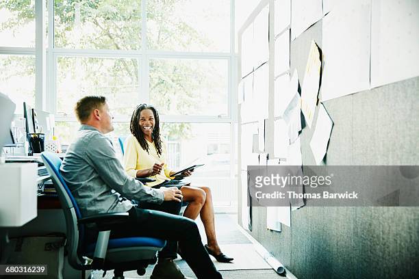 businesswoman discussing project with colleague - leanintogether stock pictures, royalty-free photos & images