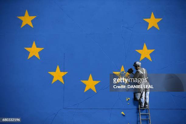 Recently painted mural by British graffiti artist Banksy, depicting a workman chipping away at one of the stars on a European Union themed flag, is...