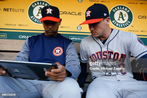 Bench Coach Alex Cora and Alex Bregman of the Houston Astros work in the dugout prior to the game against the Oakland Athletics at the Oakland...