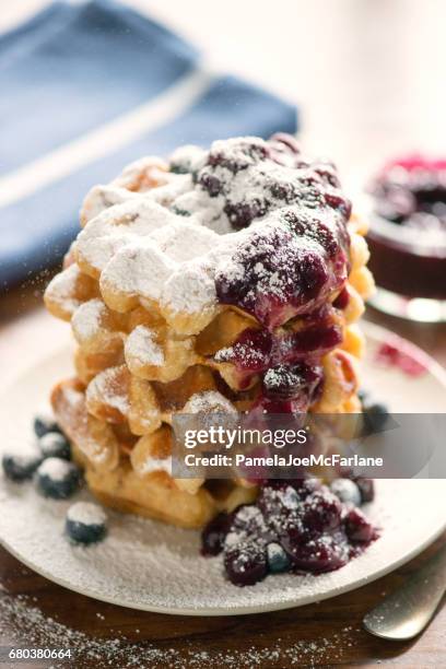 belgian waffles stack, blueberry sauce, messy and spilled icing sugar - continental breakfast stock pictures, royalty-free photos & images