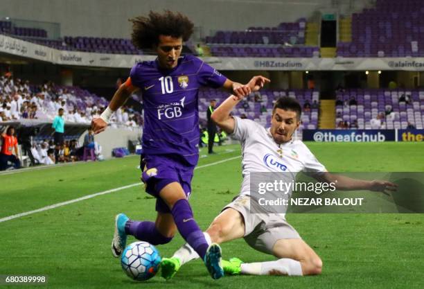 Al-Ain's Omar Abdulrahman is tackled by Bunyodkor's Komilov Akramjon during their AFC Champions League Group C football match at the Hazza Bin Zayed...