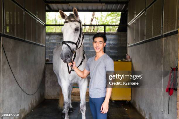 ritratto di un giovane cavaliere maschio in piedi con il suo cavallo - horse and male and riding foto e immagini stock