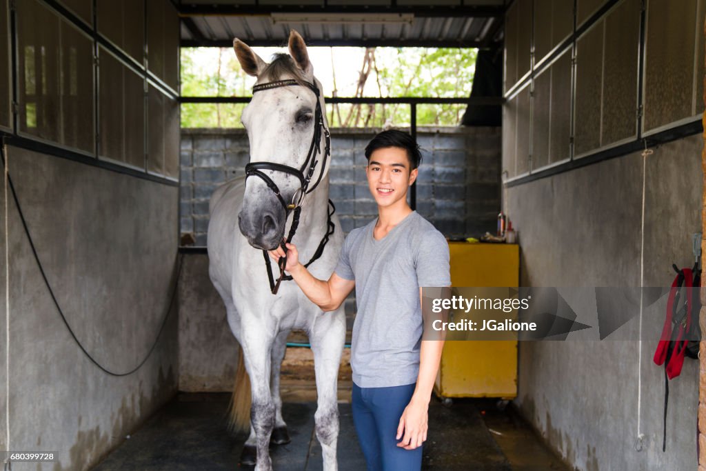 Retrato de um jovem cavaleiro masculino ficado com seu cavalo