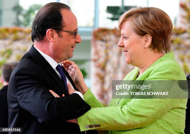 German Chancellor Angela Merkel greets outgoing French President Francois Hollande at the Chancellery in Berlin on May 8 the day after the French...