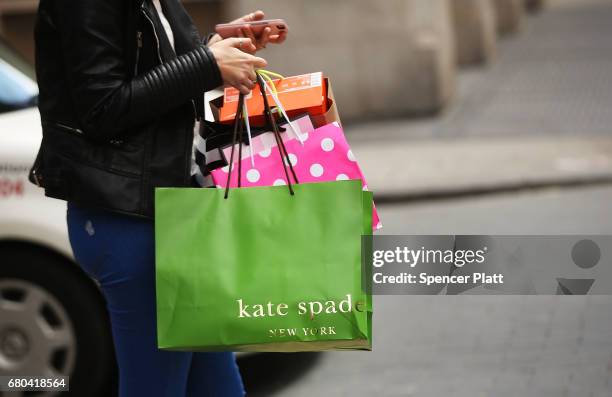 Woman walks out of a Kate Spade store in the SoHo neighborhood of Manhattan on May 8, 2017 in New York City. Coach, the American maker of high-end...