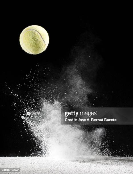 impact and rebound of a ball of tennis on a surface of land and powder on a black background - bouncing stock pictures, royalty-free photos & images