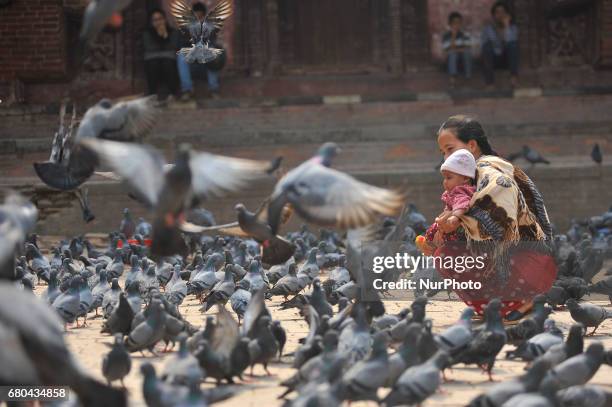 Mother helps her child to plays with pigeons at Basantapur Durbar Square, Kathmandu, Nepal on Monday, May 08, 2017. Basantapur Durbar Square is one...