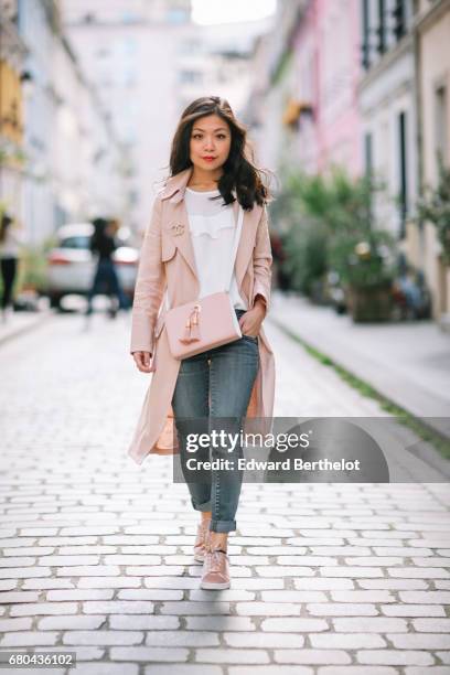 May Berthelot wears a New Look pink trench coat, a Chanel brooch, an Ame Moi pink bag, New Look sneakers, Zara jeans, and a New Look white lace top,...