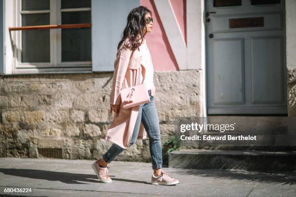 May Berthelot wears a New Look pink trench coat, a Chanel brooch, an Ame Moi pink bag, New Look sneakers, Zara jeans, and a New Look white lace top,...