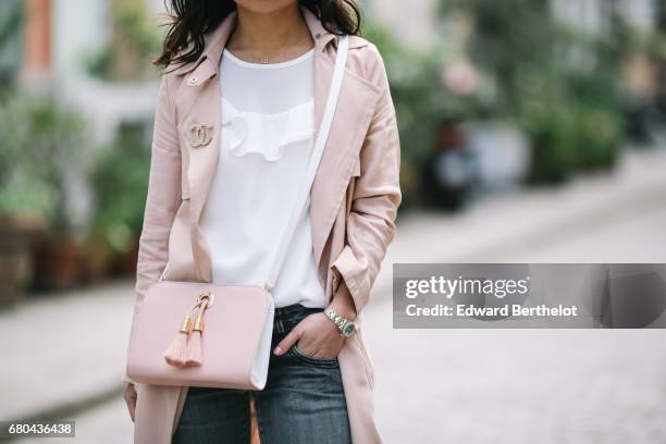 May Berthelot wears a New Look pink trench coat, a Chanel brooch, an Ame Moi pink bag, New Look sneakers, Zara jeans, and a New Look white lace top,...