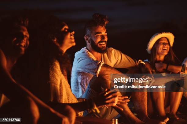 young people sitting in sand - beach music stock pictures, royalty-free photos & images