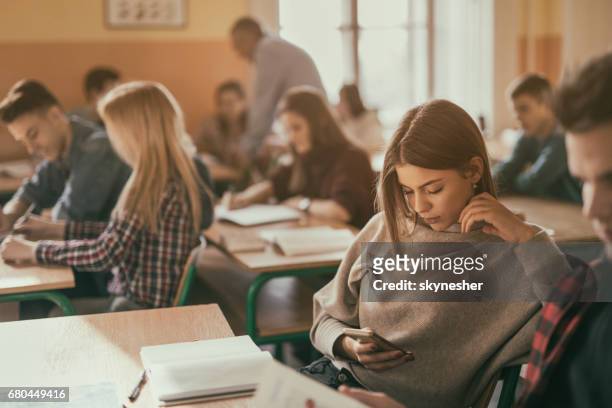 adolescente estudiante enviar mensajes de texto a teléfono celular en el aula. - mobile learning fotografías e imágenes de stock