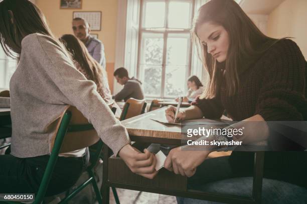 zwei high school studenten vorbei hinweis während der prüfung im unterricht. - sneaking stock-fotos und bilder