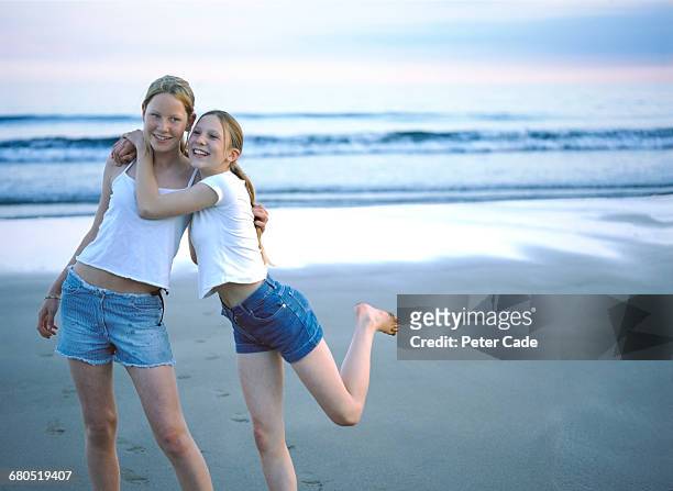 two young girls on beach - girls barefoot in jeans fotografías e imágenes de stock
