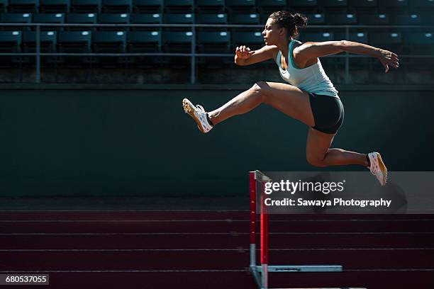 a runner taking on the hurdles. - women's track fotografías e imágenes de stock