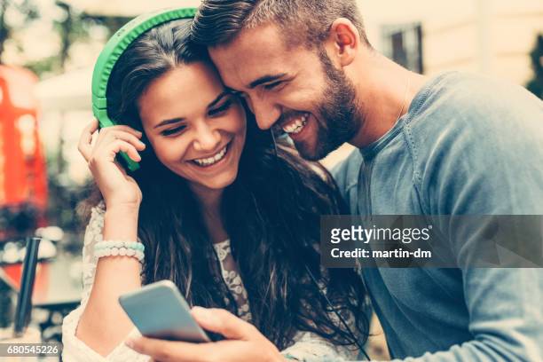 young couple playing songs from mp3 player - sharing headphones stock pictures, royalty-free photos & images