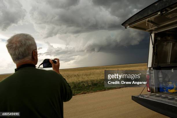 Tim Marshall, a 40 year veteran of storm chasing, gets out of the tornado scout vehicle for a better view of a supercell thunderstorm during a...