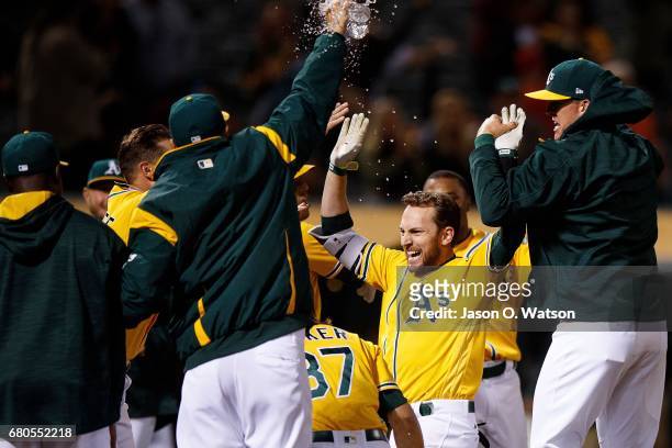 Jed Lowrie of the Oakland Athletics celebrates with teammates after hitting a walk-off home run during the eleventh inning against the Los Angeles...