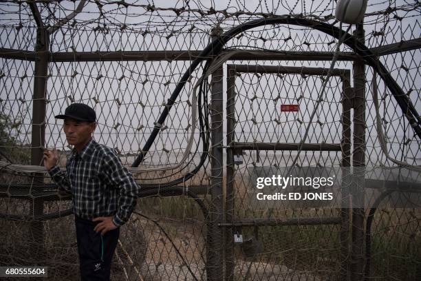 Farmer In-Suk Hwang stands outside his home next to the fence of the Demilitarized Zone on Gyodong, a tiny outlying island near to the west of Seoul,...