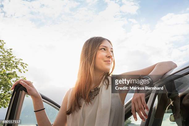 confident woman leaning at her new car - leunen stockfoto's en -beelden