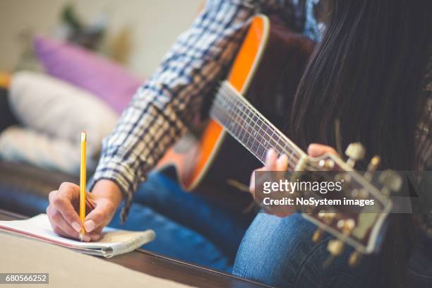 close up van meisjes hand opschrijven van muziek, een gitaar spelen. ondiep dof, focus aan kant en potlood. - singing stockfoto's en -beelden