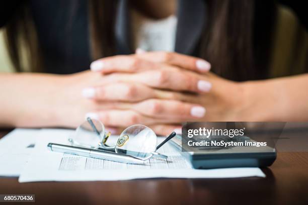 primo piano di mani di imprenditrici con penna, occhiali e calcolatrice facendo alcuni calcoli finanziari - busta paga foto e immagini stock