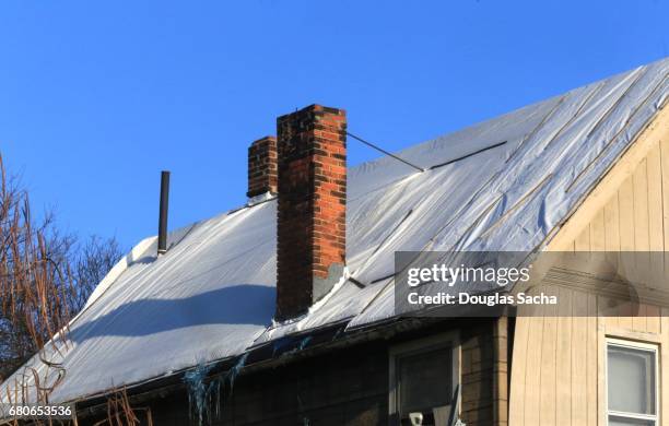 damaged building roof covered in plastic tarp - diy disaster stock pictures, royalty-free photos & images