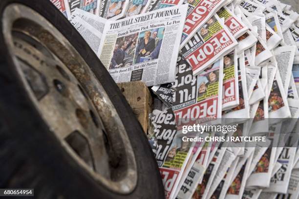 Copy of the Wall Street Journal is pictured underneath a wheel of a Jeep automobile as Turner Prize nominated artist David Mach works on his...