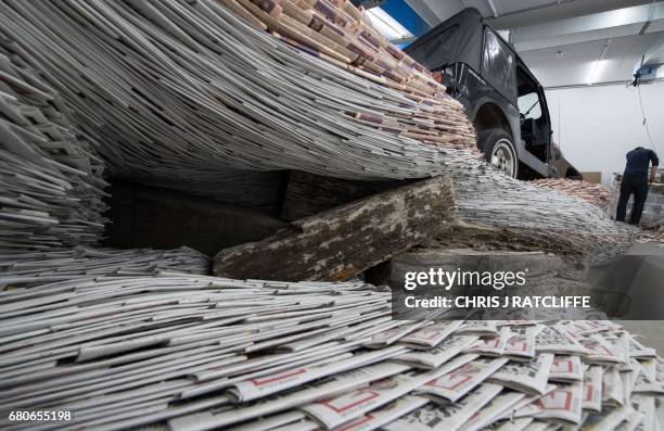 Assistant Mac McNaughton cuts newspapers as he helps works with Turner Prize nominated artist David Mach , on the installation 'Incoming' at the...