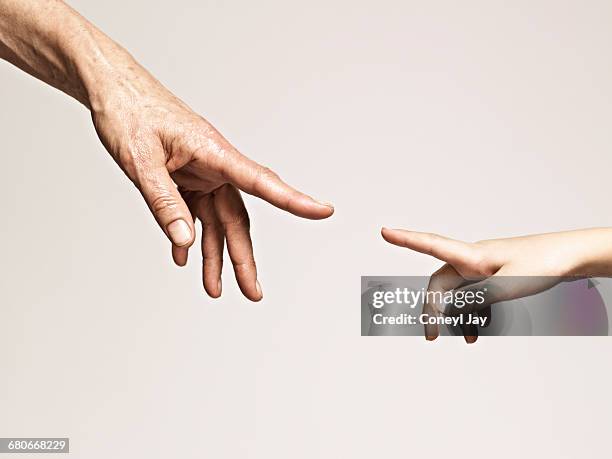 young and old hands point together - touching imagens e fotografias de stock