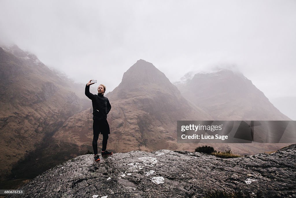 A runner takes a selfie on a mountain in Scotland