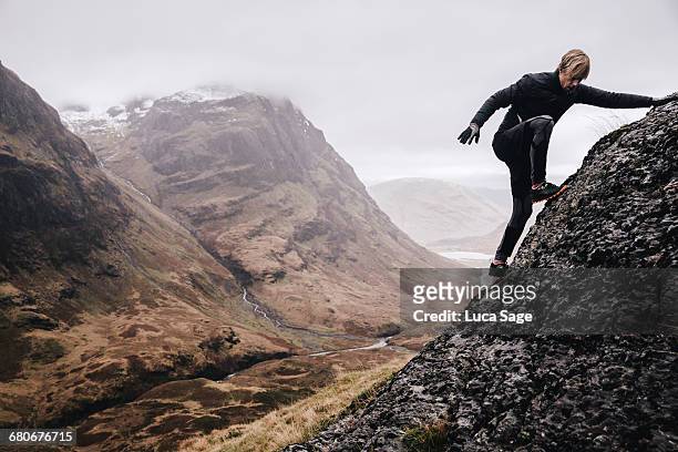 a free runner climbs a steep mountain rock face - aufgabe stock-fotos und bilder