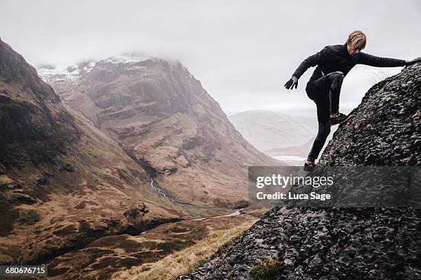 a free runner climbs a steep mountain rock face - reto fotografías e imágenes de stock