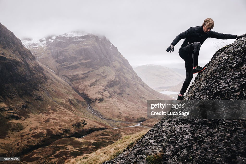 A free runner climbs a steep mountain rock face