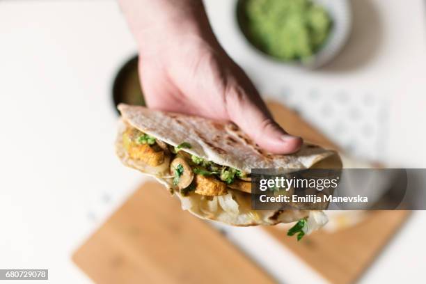 human hand holding homemade chicken taco - wrap sandwich stock-fotos und bilder