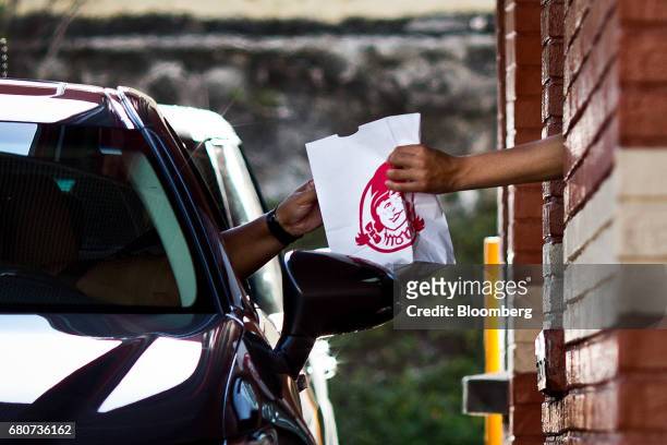 Worker passes a bag of food to a customer at the drive-thru window of a Wendy's Co. Restaurant in Miami, Florida, U.S., on Wednesday, May 3, 2017....