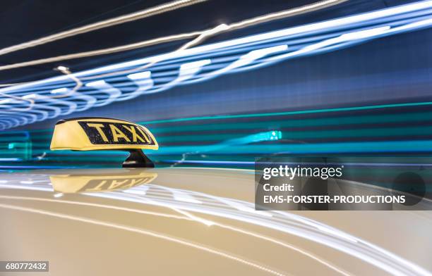 automotive on board a driving car long exposure rigging shot from the top of a german taxi. dirty taxi roof sign board / dachzeichen in foreground. reflections in the roofs surface of the cab. background is motion blurred and tunnel lights are streaking. - lackiert stock-fotos und bilder